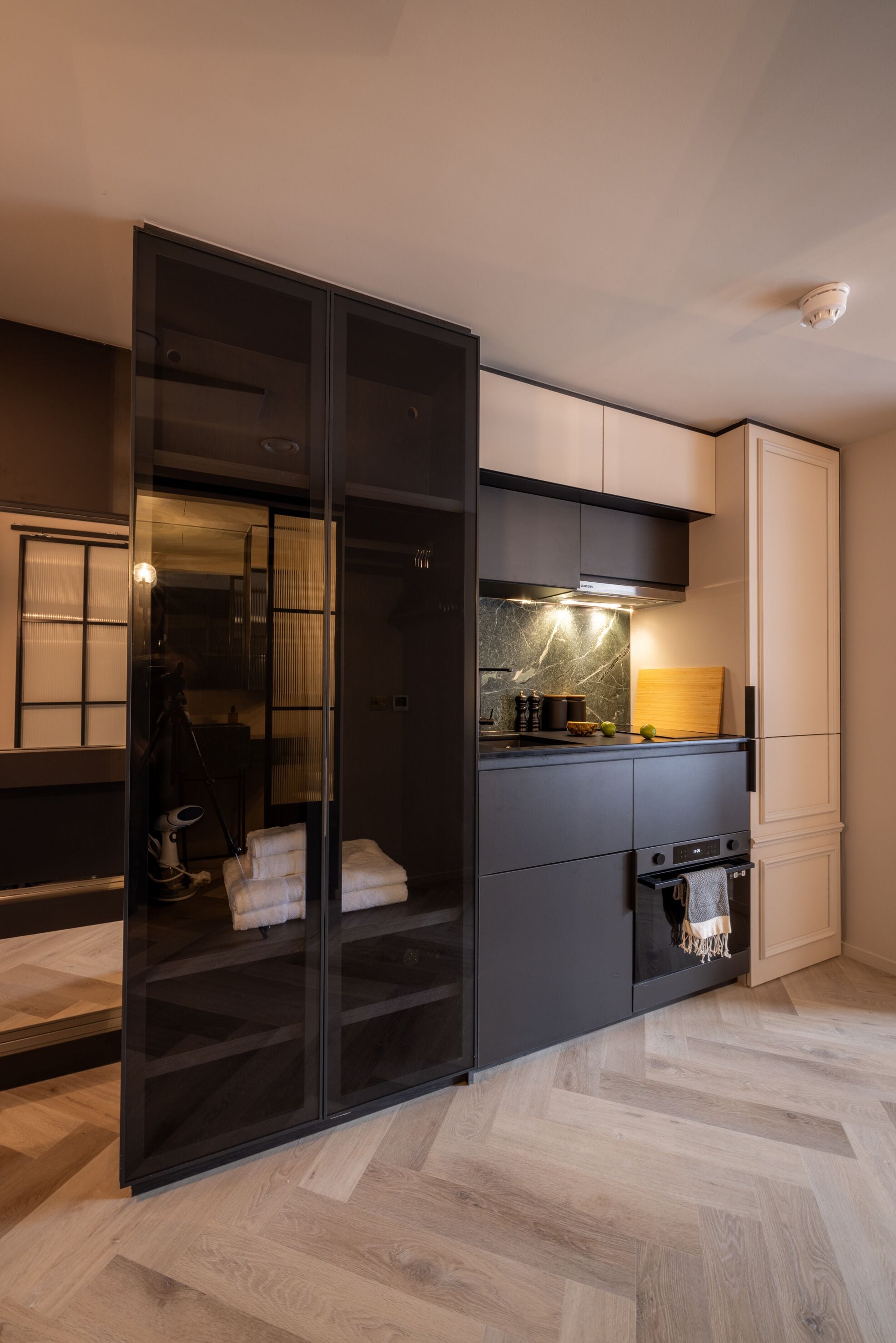 A modern kitchen with a built-in oven, a microwave, and a stove. There is a sliding door leading to a storage area.