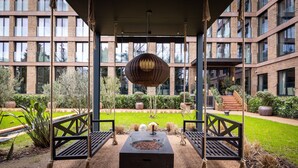A courtyard with a fire pit, swings, and a hanging lamp.
