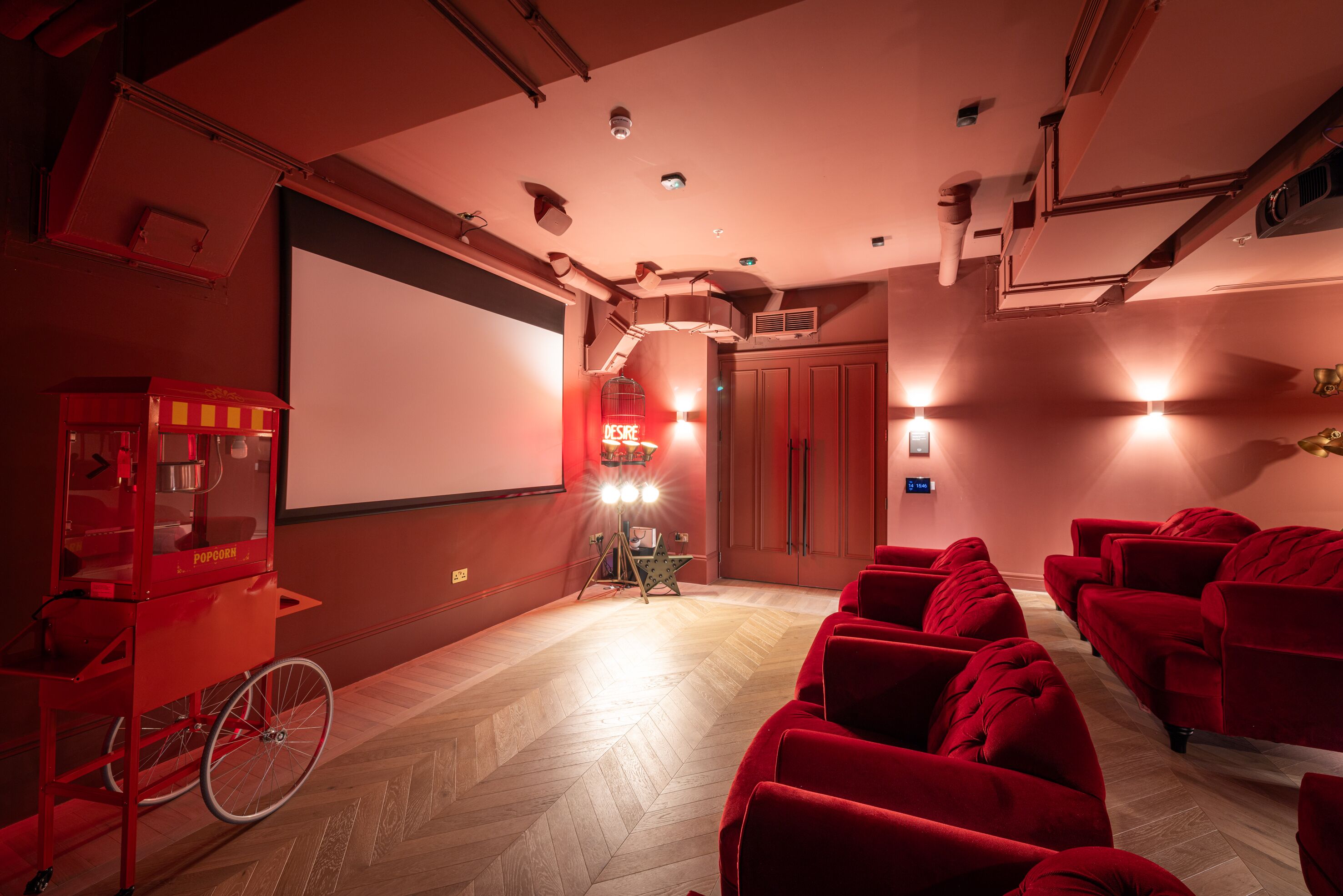 Une salle de cinéma avec des sièges rouges, un distributeur de pop-corn et un écran de projection.