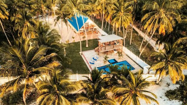 A resort with a pool, lounge area, and palm trees.