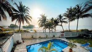 A swimming pool with a view of the beach and palm trees.