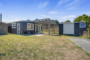 A residential property with a covered patio, a fenced garden, and a small shed.