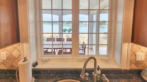 Een badkamer met een groot raam met uitzicht op een meer en een terras.