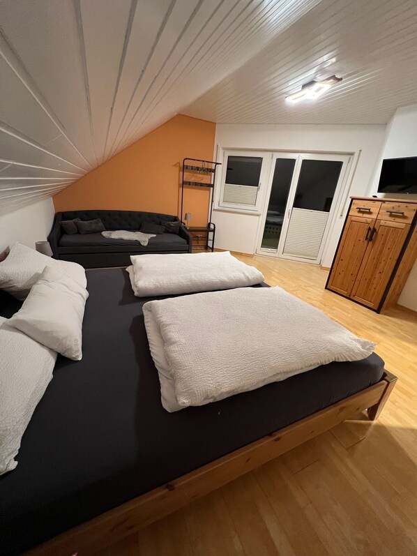 Un dormitorio con una cama individual superior e inferior, un sofá, un armario y una ventana con persianas.