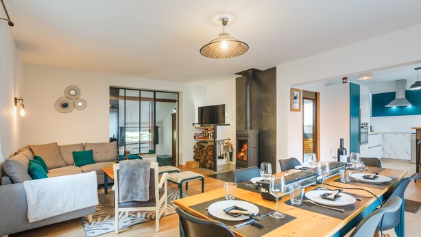A modern living room with a sofa, dining table set for four, and a fireplace. - Maison Individuelle, Terrasse et Jardin Clos (Cauterets)