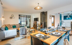 A modern living room with a sofa, dining table set for four, and a fireplace. - Maison Individuelle, Terrasse et Jardin Clos (Cauterets)