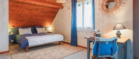 A bedroom with a bed, bedside table, lamp, chair, and a wall-mounted mirror.