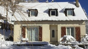 A two-story house with a snow-covered roof and a small garden area in front. - Maison Individuelle, Terrasse et Jardin Clos (Cauterets)