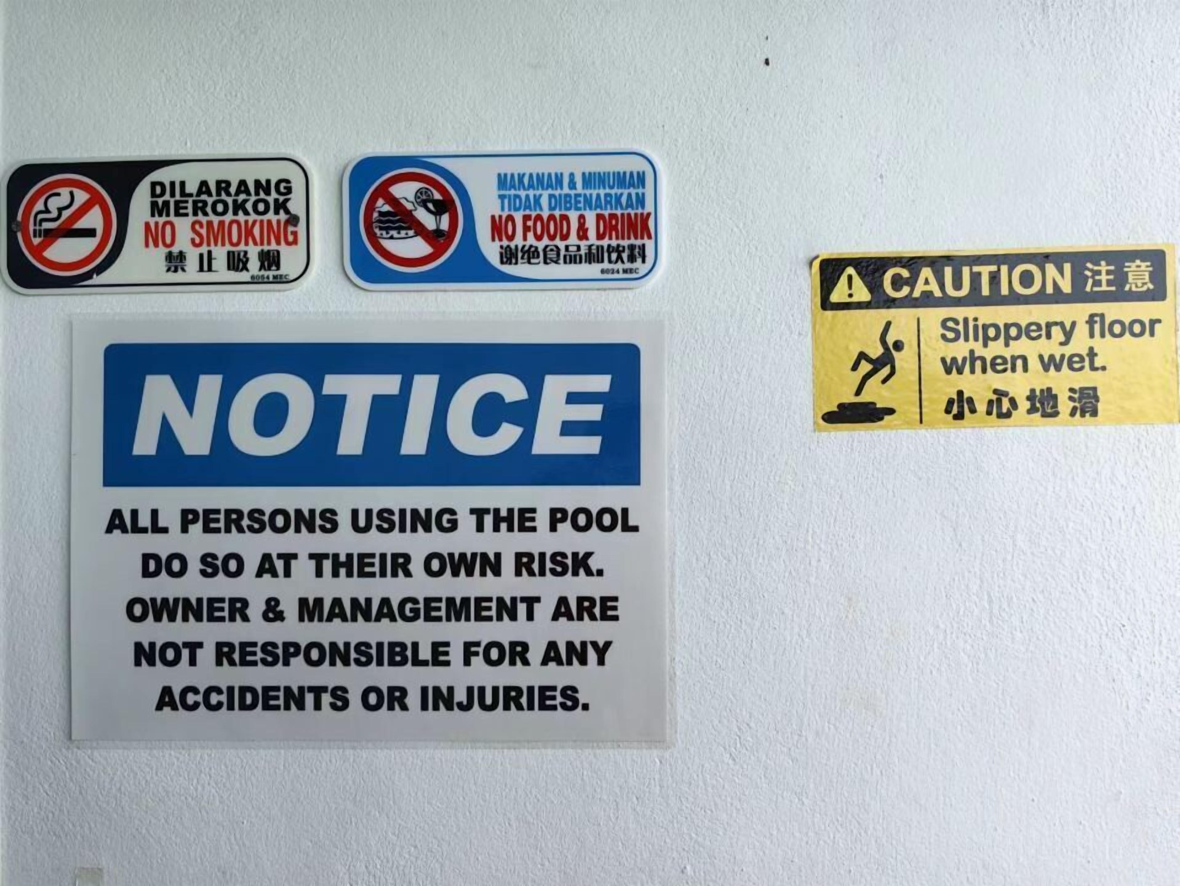 Multiple safety and usage signs on a wall, including no smoking, no food and drink, and a caution for slippery floors when wet.