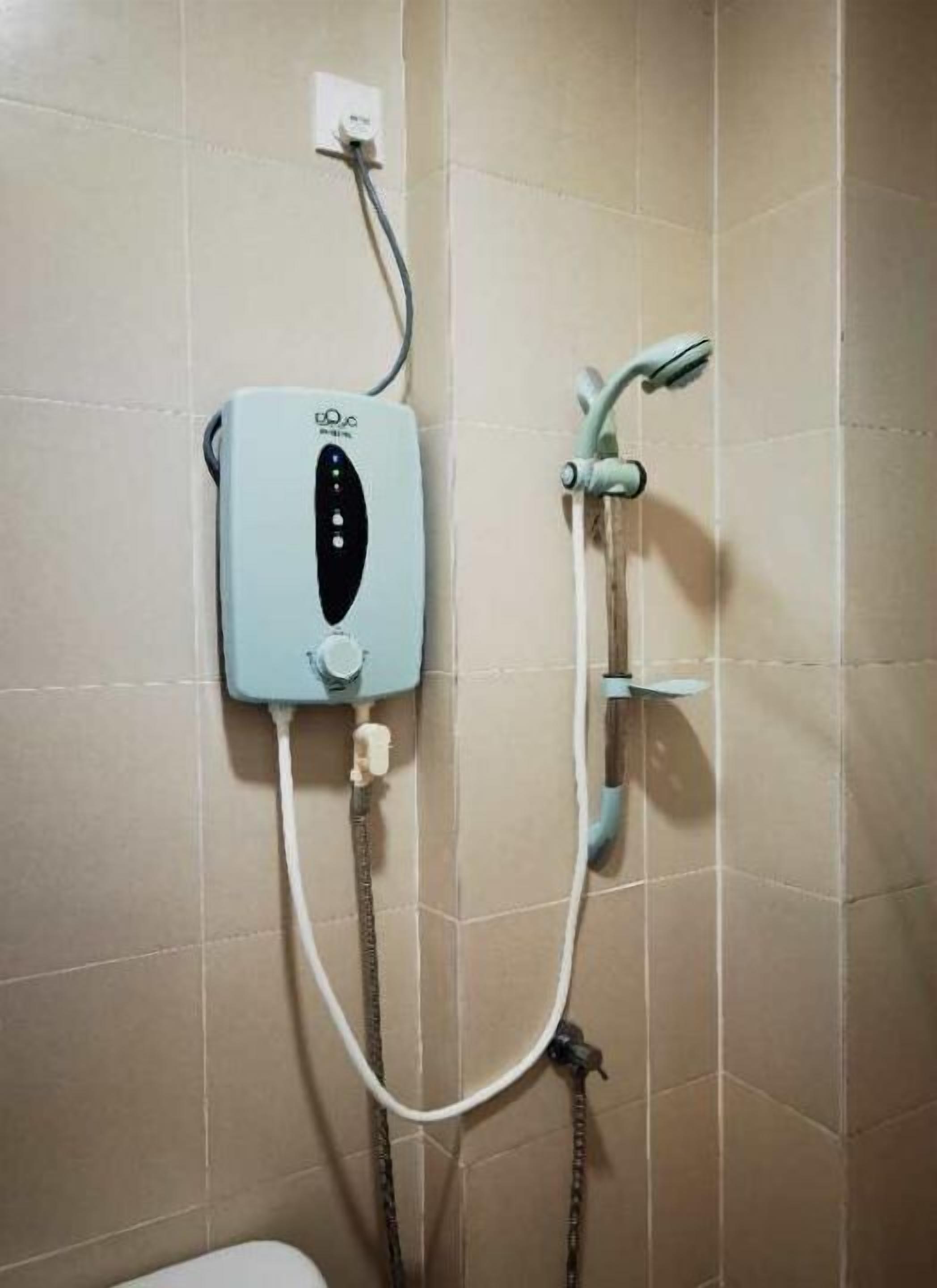 A bathroom with a wall-mounted shower unit, including a control panel and a handheld showerhead.