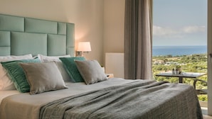 Ein Hotelzimmer mit einem großen Bett, Meerblick und einem Balkon mit Pflanzen.