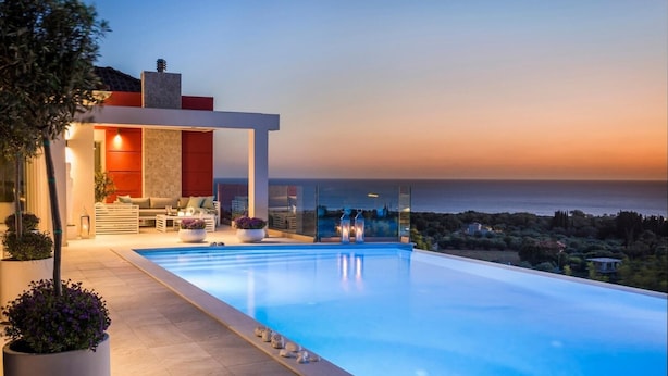 Ein moderner Infinity-Pool mit freiem Blick auf das Meer bei Sonnenuntergang.