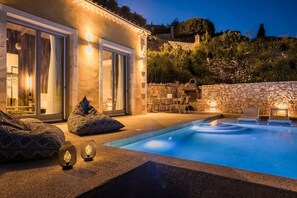 Ein moderner Poolbereich im Freien mit einer Steinmauer, einem Whirlpool und einer Essgruppe.