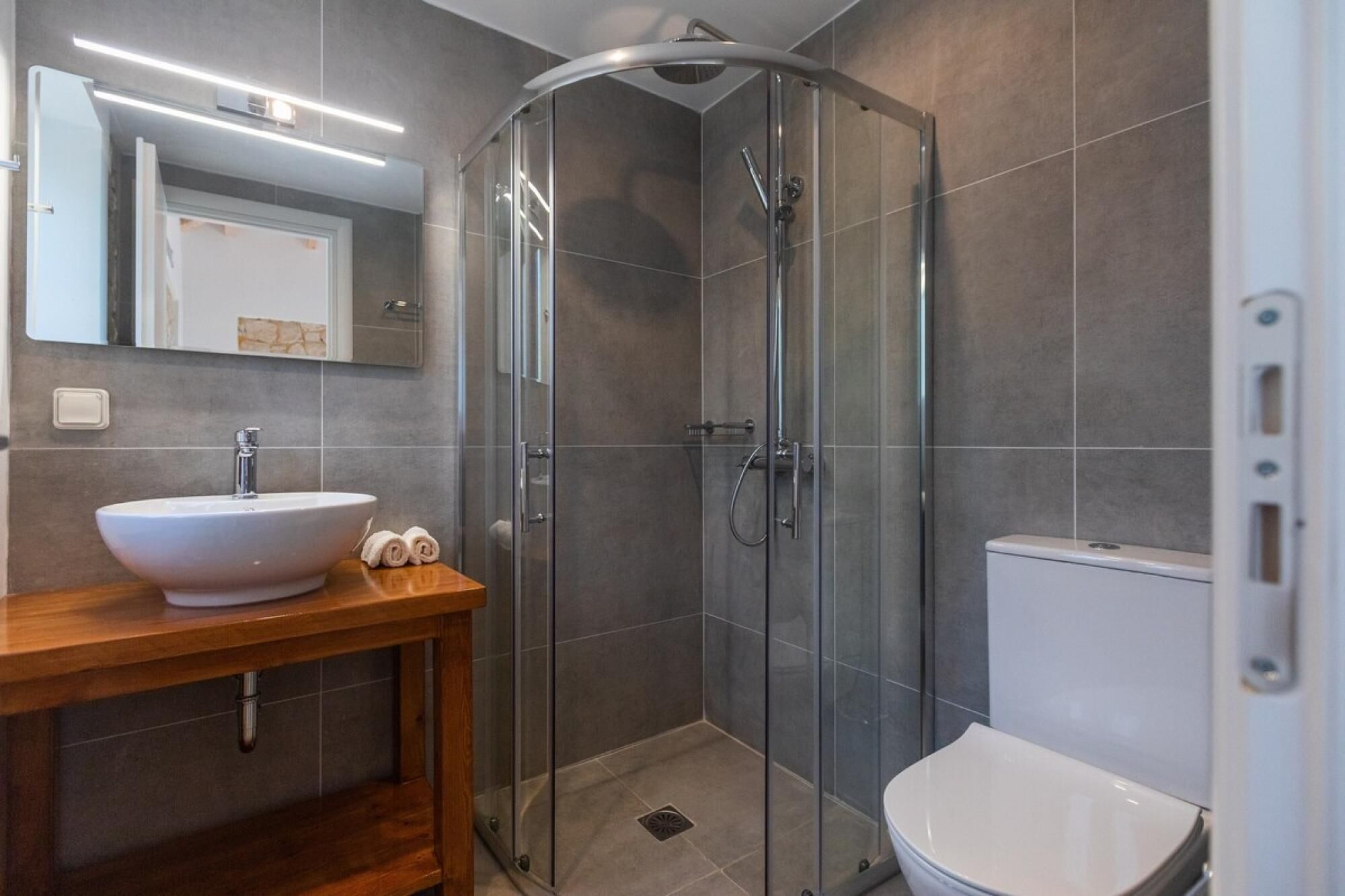 Ein modernes Badezimmer mit Duschkabine aus Glas, einem weißen Waschbecken und einer Toilette.