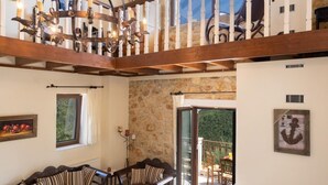 A spacious living area with a high ceiling, a fireplace, and a balcony with a stone wall. - Villa Bolios Sea View Private Pool (Kefalonia)