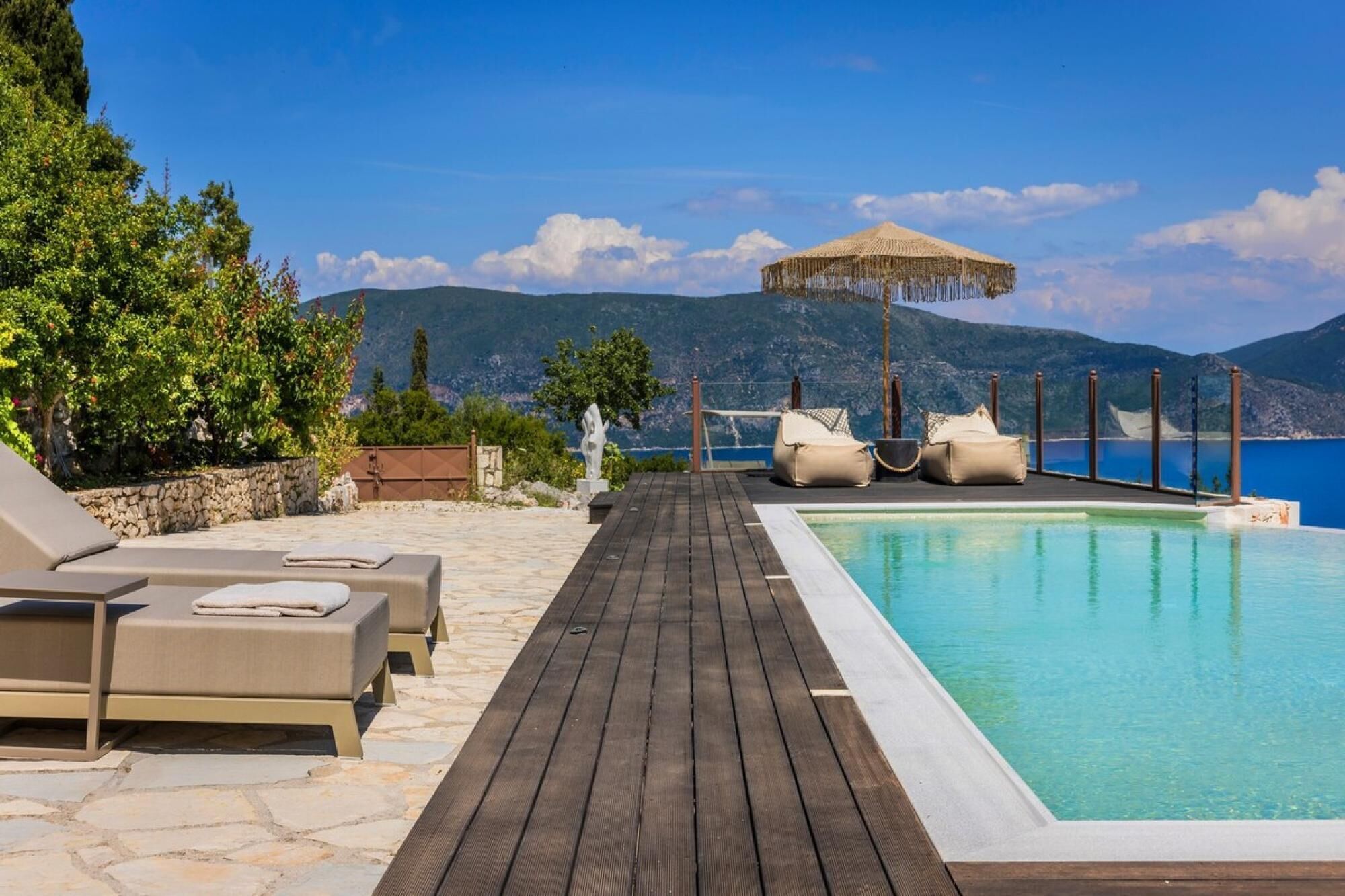 Una terraza de madera con sillones de descanso y una piscina.