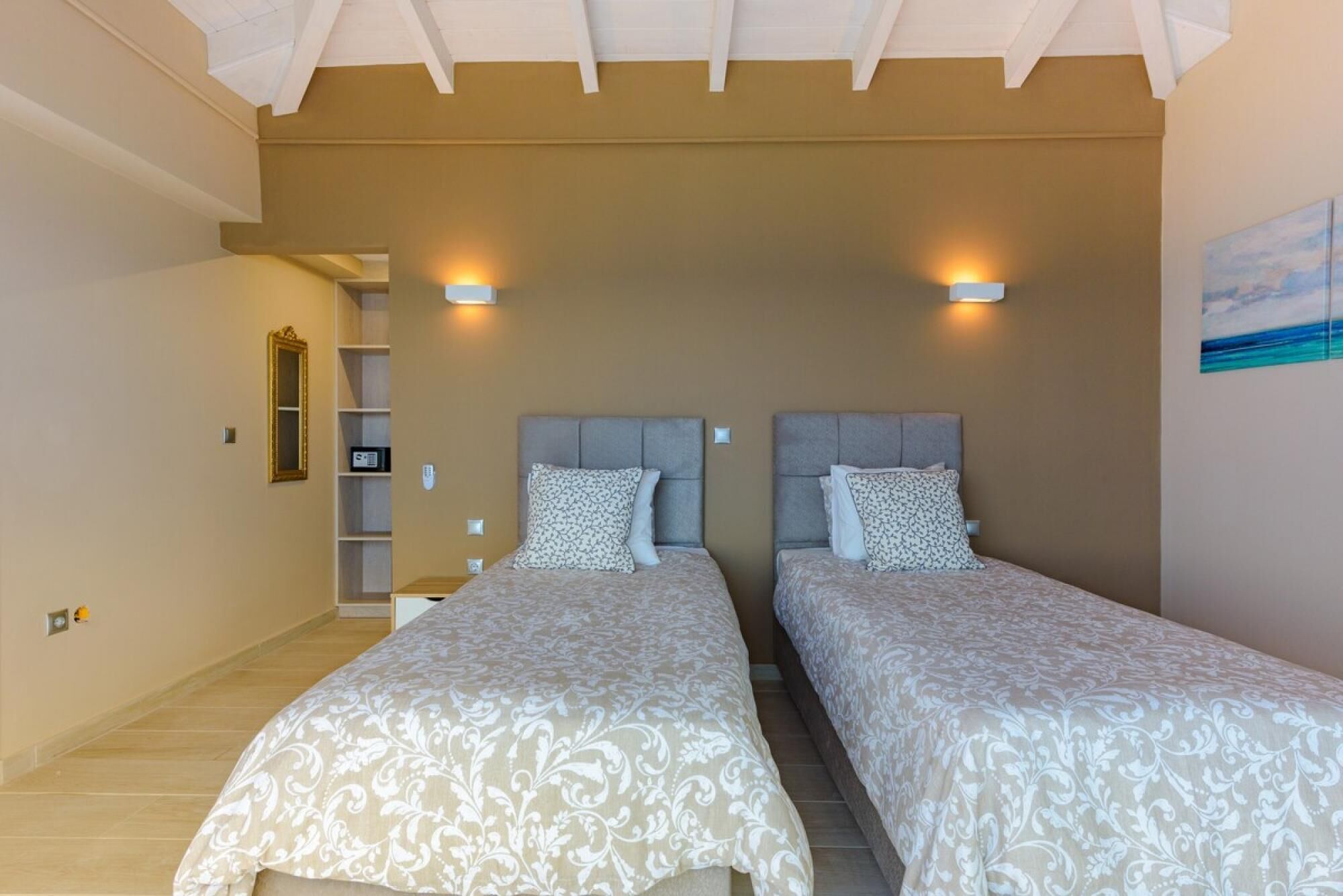 A bedroom with two beds, a bookshelf, and a painting on the wall.