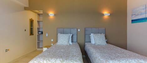 A bedroom with two beds, a bookshelf, and a painting on the wall.