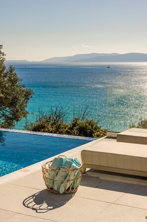 A poolside area with a clear view of the sea and mountains in the background. - My Villa Kefalonia Lourdas Beach (Kefalonia)