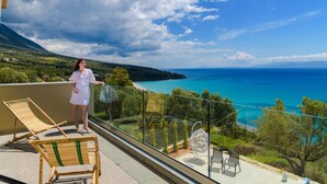 A balcony with a clear view of the sea, a wooden chair, and a hanging chair.