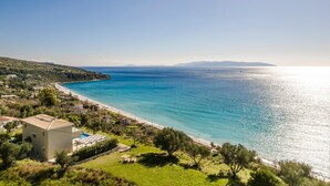 A coastal property with a swimming pool, a beach, and a view of the sea.