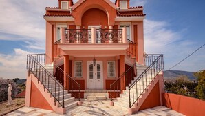 Una casa de dos pisos con un balcón, una escalera y vista al paisaje.