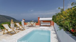 Un área de piscina en la azotea con sillones de descanso, una mesa y una parrilla.