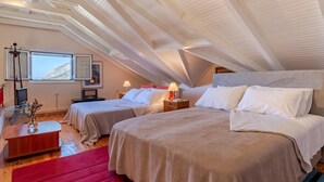 Un amplio dormitorio en el ático con dos camas, piso de madera y techo inclinado.