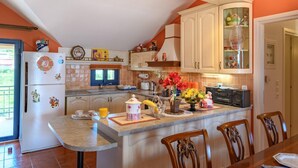 A kitchen with a central island, wooden cabinets, and a dining area with chairs. - Entheos City Panorama Argostoli (Kefalonia)