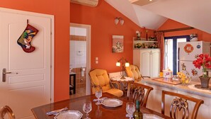 A dining area with a table set for four, a kitchen with a refrigerator, and a bathroom visible through an open door. - Entheos City Panorama Argostoli (Kefalonia)