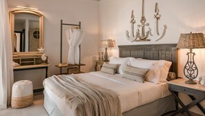 A bedroom with a bed, a nightstand, a lamp, a mirror, and a wall-mounted light fixture. - Casa Grec Villa Kefalonia (Kefalonia)