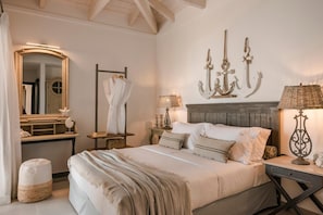 Quarto com cama, mesa de cabeceira, luminária, espelho e luminária fixada na parede.