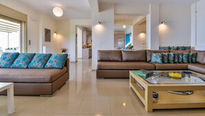 A spacious living room with two sofas, a coffee table, and a view into the kitchen. - Infinite Blue Epidavros (Epidaurus)