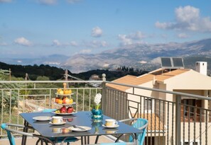 A balcony with a table set for breakfast, overlooking a mountainous landscape. - Belle Helens Villa Kefalonia (Kefalonia)