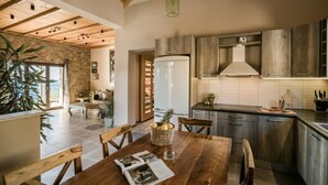 Eine moderne Küche mit Holzausstattung, einem eingebauten Backofen und einer Essecke mit Holztisch und Stühlen.