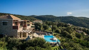 Eine Villa mit Swimmingpool, Steinmauern und Blick auf die umliegenden Hügel.
