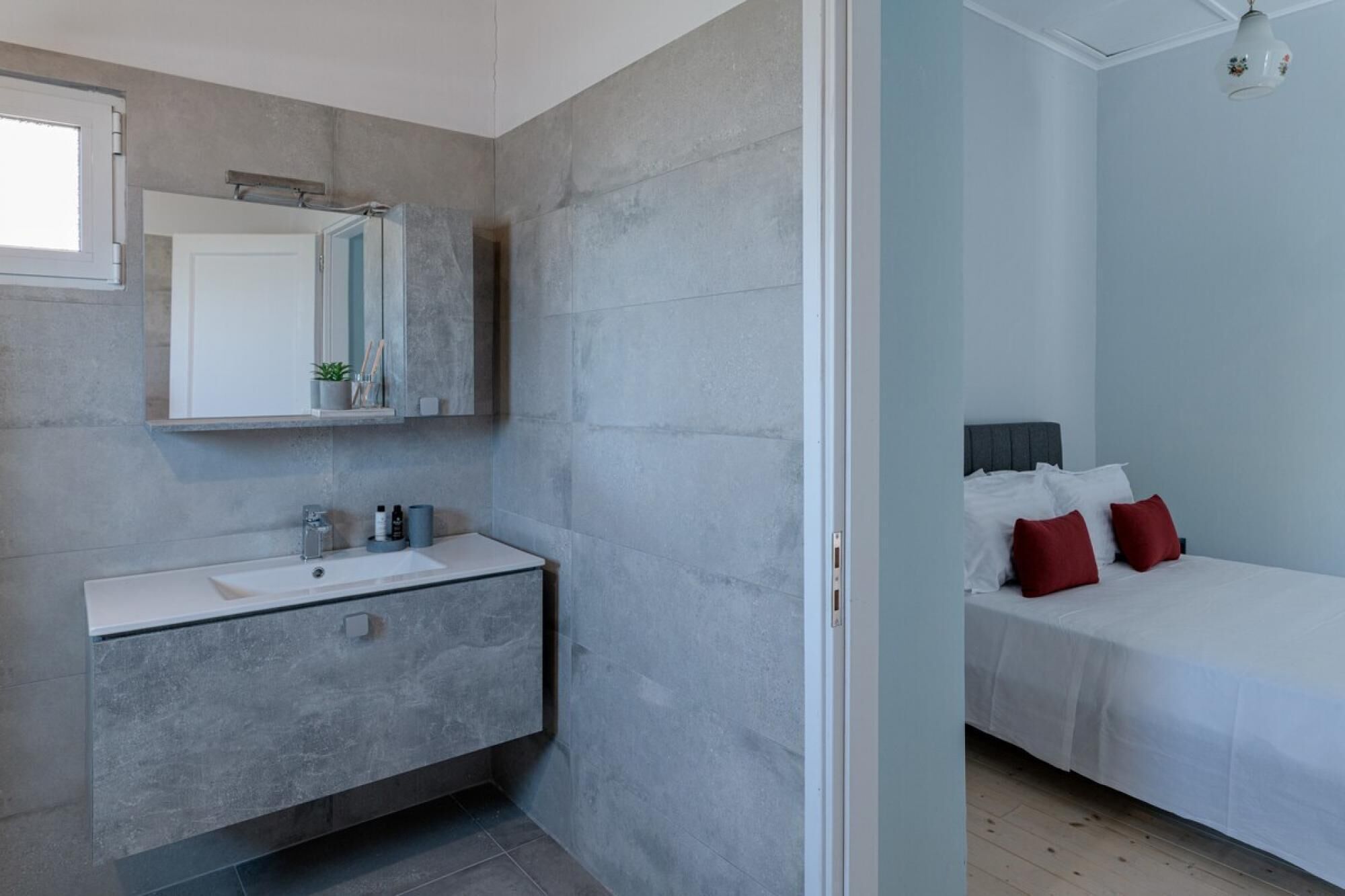 A modern bathroom with a white vanity, a large mirror, and a shower area.