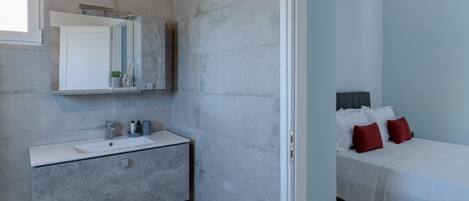 A modern bathroom with a white vanity, a large mirror, and a shower area.