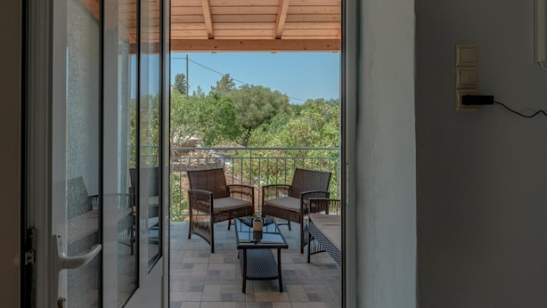 A balcony with wicker furniture and a view of trees. - Magganos House II Kefalonia (Kefalonia)