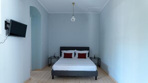 A bedroom with a bed, two bedside tables, a wall-mounted TV, and a ceiling light. - Magganos House II Kefalonia (Kefalonia)