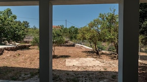 A view through a covered outdoor area with a dirt ground and trees. - Magganos House Kefalonia (Kefalonia)