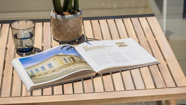 A glass table with a magazine, a potted plant, and a glass of water. - Casa Simone Kefalonia (Kefalonia)