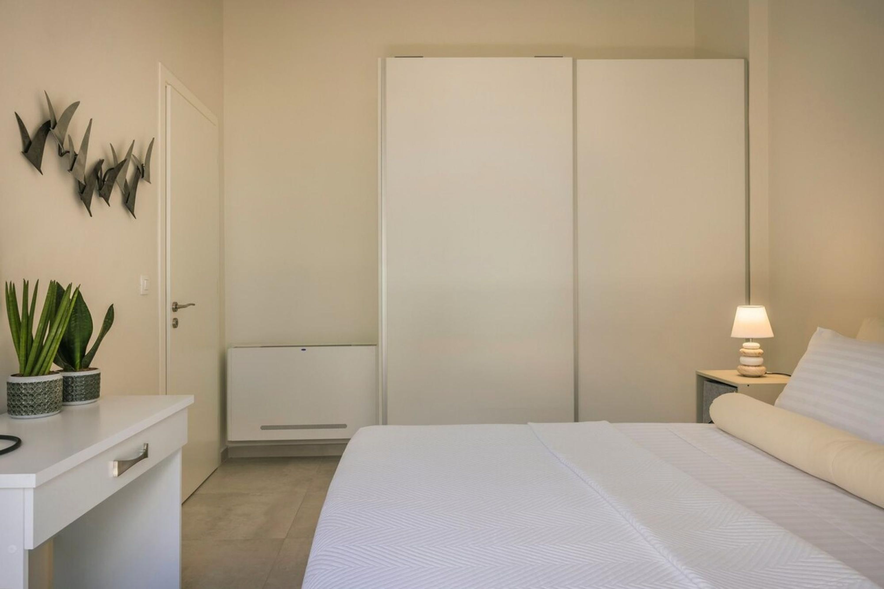 A bedroom with a bed, bedside table, lamp, and a wardrobe.
