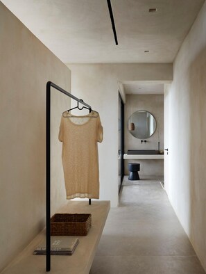 A minimalist hallway with a hanging garment rack, a mirror, and a small basket with books.