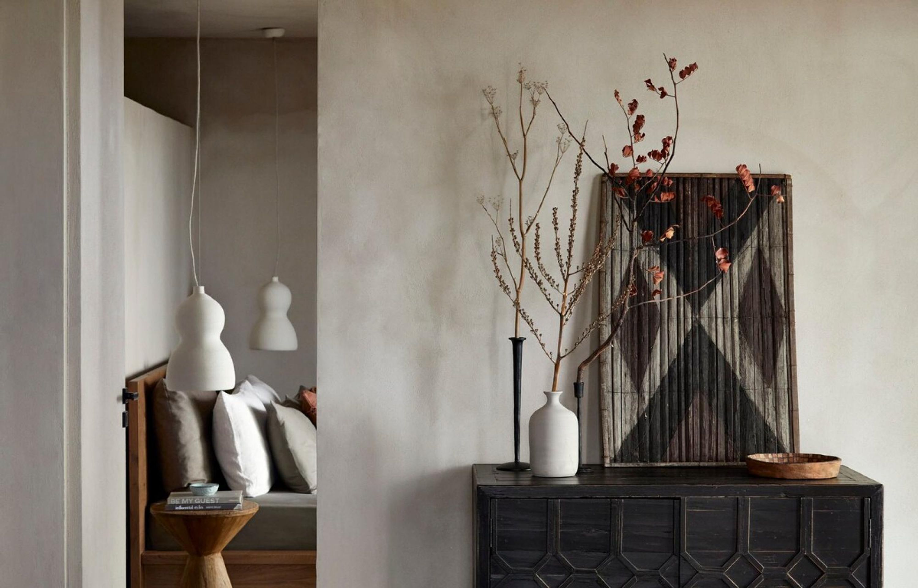 Una sala de estar moderna con un sofá, una mesita auxiliar con un libro y un jarrón decorativo con ramas.