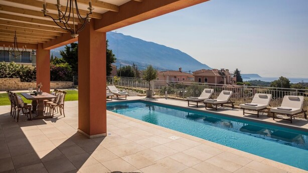 Un espace piscine avec des chaises longues, une table et une vue sur les montagnes.
