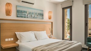 A modern bedroom with a wooden headboard, a large bed with white linens, a painting of sailboats, and a view of the outdoors through a glass door. - Villa Nefeli - Ionian Treasure Villas (Kefalonia)