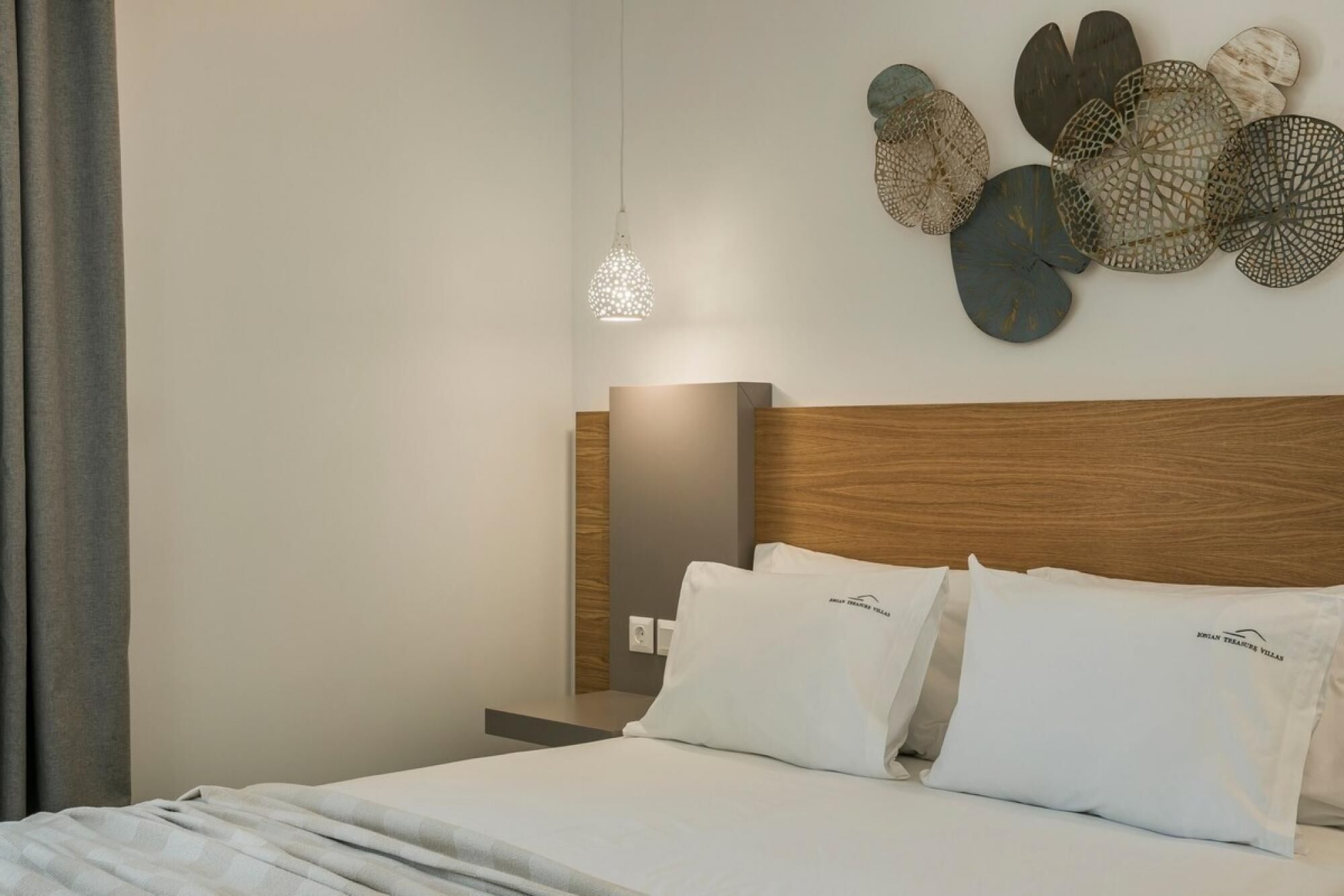 Ein modernes Hotelzimmer mit einem Holzkopfteil, einem großen Bett mit weißer Bettwäsche und dekorativer Wandgestaltung.