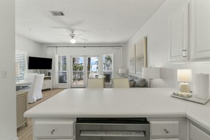 A spacious kitchen with a large island, white cabinetry, and a ceiling fan.