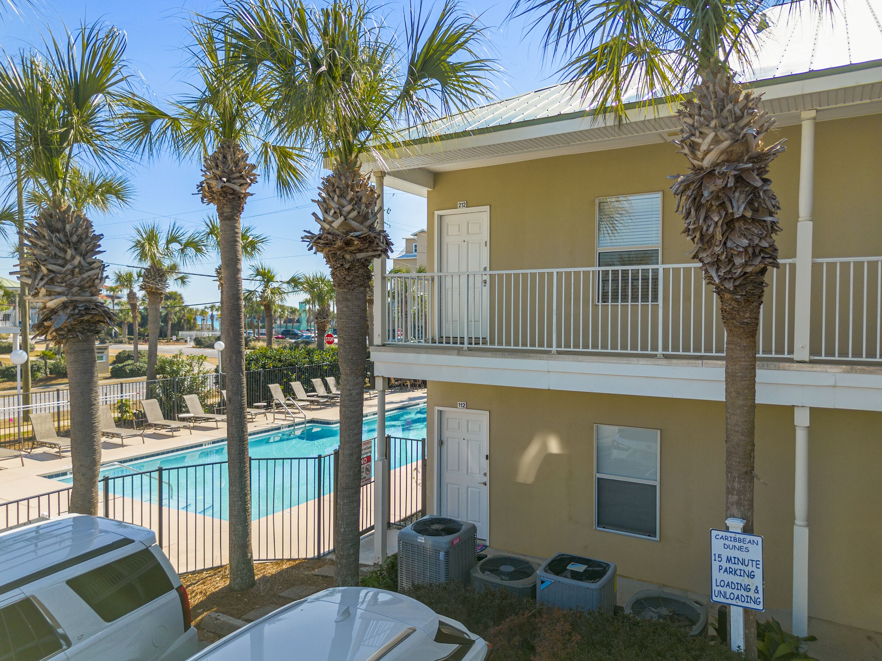 A two-story building with a pool, palm trees, and a sign indicating 15-minute parking.